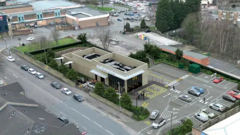 A McDonald's restaurant pictured from above. It is flanked by roads on two sides.
