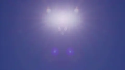 Shot of a dazzling white blurred sun sitting high in the sky on a bright blue summer's day 