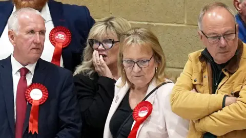 Labour party activists look on as ballot papers are counted for the 2026 Essex County Council election at Clacton Leisure Centre in Essex