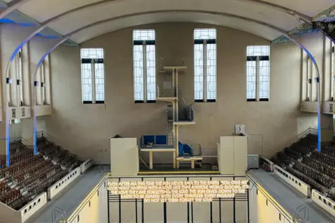 Artwork inside art deco swimming pool, words are lit up.