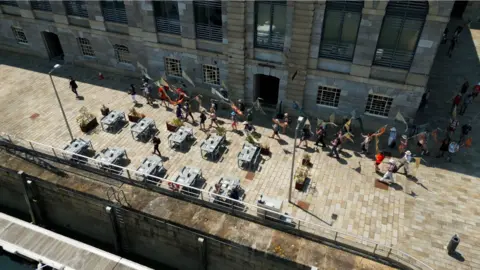 Jay Stone People walking with silk flags on Royal William Yard 