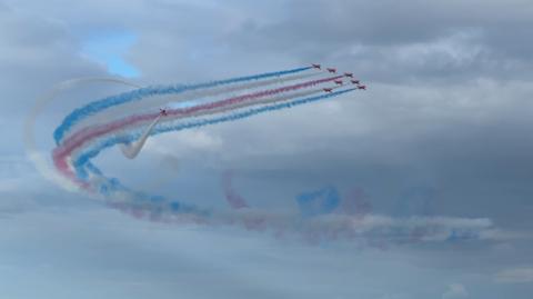 The Red Arrows in formation with blue and red smoke coming from their tails