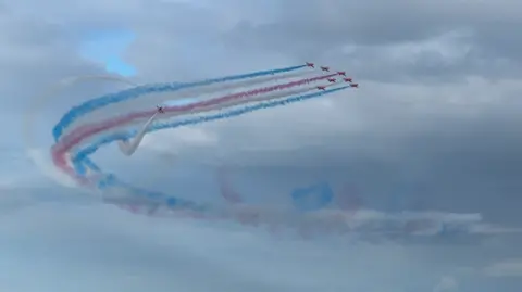 BBC The Red Arrows in formation with blue and red smoke coming from their tails