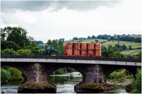 Julie Charles A tractor pulls a trailer of hay crossed  a bridge