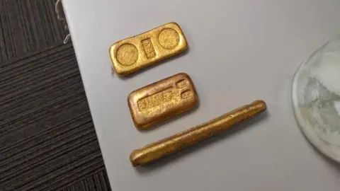 A picture or part of the find from the beach. It’s three items all gold in colour