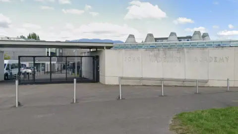 A general view picture of the John Madejski Academy in Reading, which has a stone wall with "John Madesjski Academy" carved into it.