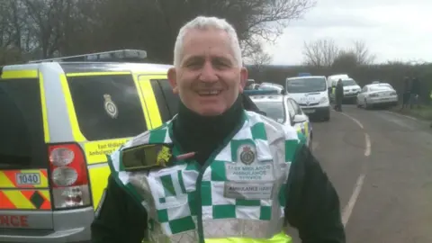 EMAS Dave Turner stood on a road wearing East Midlands Ambulance uniform