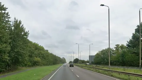 A two-laned road with traffic lights in the central reservation