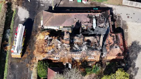 Eddie Mitchell A destroyed pub building with a fire engine on the road to the left