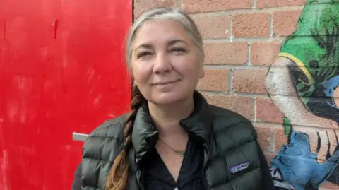Indra Donfrancesco Cllr Donfrancesco standing in front of a wall looking at the camera