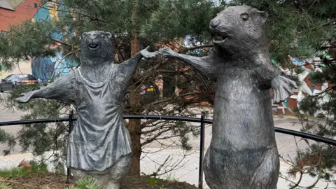 Two statues of beavers. They are grey.