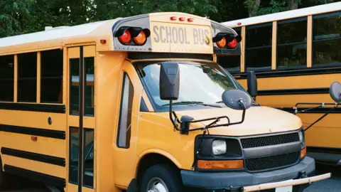 A yellow American school bus parked in a car park