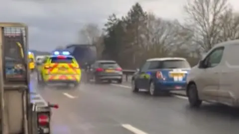 West Kent Sport & Wellbeing An emergency vehicle driving between two lanes of queuing traffic in heavy rain on a carriageway