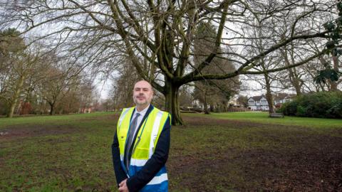 Man in a high vis jacket standing in front of a tree