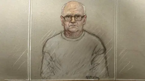 Julia Quenzler A court sketch of a balding man wearing glasses and a grey sweatshirt, standing behind glass 