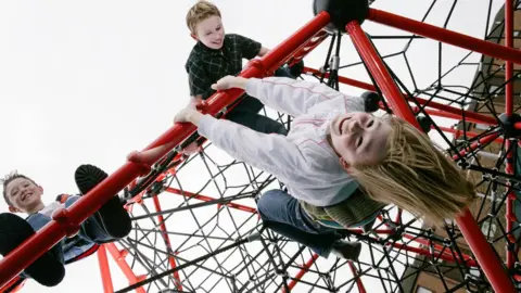 Science Photo Library Children playing on a climbing frame