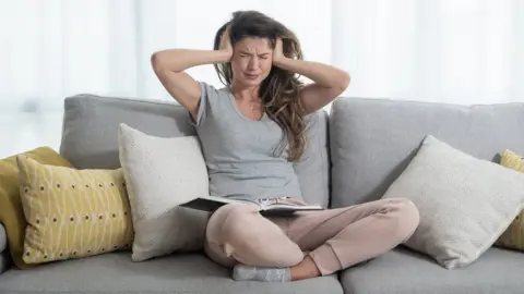 Getty Images woman on sofa with hands over her ears