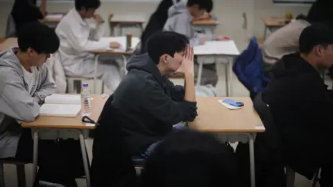 Students wait for the start of the annual college entrance examinations, also known as Suneung, at an exam hall in Seoul