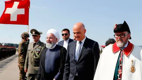 AFP Iranian President Hassan Rouhani (3rd left) walks with Swiss Federal President Alain Berset (C) at an airport in Kloten on 2 July 2018