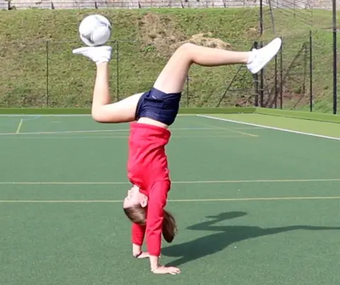 Isabel, 16, doing a hand stand and balancing a football