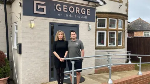 Justin Dealey/BBC Simon and Louise Babikian standing outside The George pub