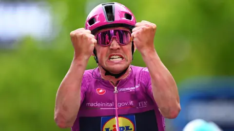 Danish cyclist Mads Pedersen raises his fists in celebration after winning stage three of the 2025 Giro d'Italia