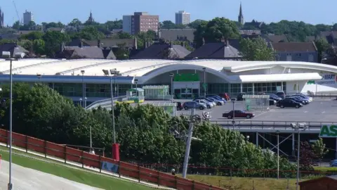 Colin Smith/Geograph Asda car park, viewed from the dry ski slope next door. Houses and other buildings can be seen in the background. 