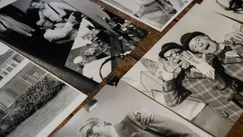 PA Media Several black-and-white photographs are laid out on a table