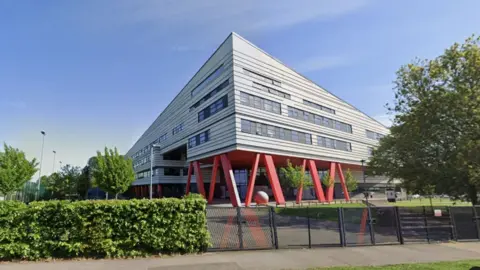 Exterior of Marvell College. A modern triangular building with red supporting pillars.