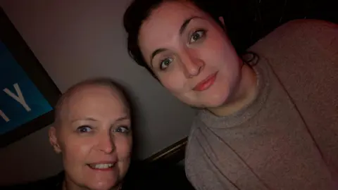 Louise Palmer A selfie of Louise and Katie. Louise has a shaved head, and Katy has long black hair and is wearing a grey top.