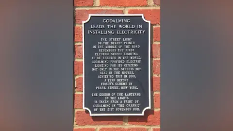 BBC/Simon Furber A plaque in Godalming paying tribute to it being the first place to provide electricity to a town.