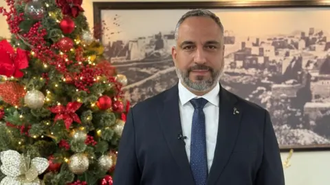 O prefeito de Belém, Maher Canawati, ao lado de uma árvore de Natal com enfeites vermelhos e dourados