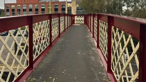 A burgundy and gold coloured metal bridge 