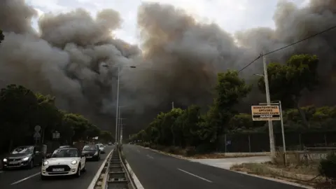 EPA Smoke rise over an avenue during a forest fire in Neo Voutsa, a north-eastern suburb of Athens, Greece, 23 July 2018.