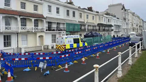 A police cordon in place on St Leonards seafront with a police van and plastic barriers