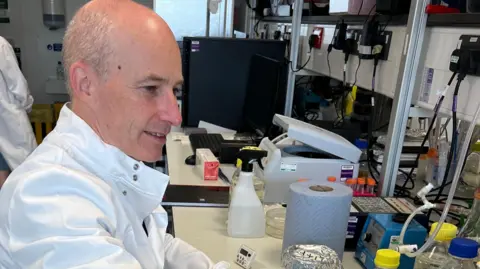 Cancer Research UK handout A side view of Prof Stephen Taylor in a medical lab wearing a white lab coat. 