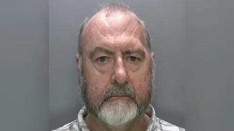 Sussex Police A police mugshot of Ivor Whittaker in which he looks at the camera and a pale checked shirt can just be seen. He has a gray-white beard