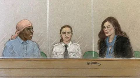 Julia Quezler A court sketch showing Constance Marten, a woman with long brown hair wearing a dark top, and Mark Gordon, who has a peach-coloured headscarf and is wearing a shirt, looking at each other past a dock officer while sitting in a glass dock in court. The dock officer is a woman wearing a white shirt and black tie, with brown hair tied back and to the side