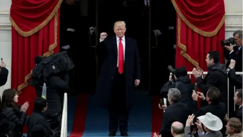 Getty Images Donald Trump raising a fist, surrounded by cameras, arriving to his inauguration ceremony