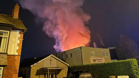 Joe Pugh A row of buildings in Abergavenny, including houses and a nursery, with plumes of smoke billowing behind them