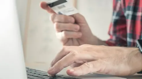 Science Photo Library Man typing credit card details out