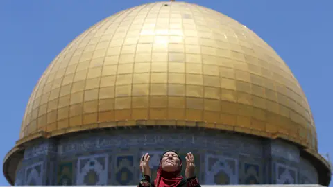 Reuters A Palestinian woman prays in front of the Dome of the Rock