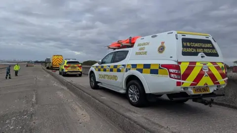 Wirral Coastguard Rescue Team An HM Coastguard vehicle and other emergency vehicles are parked along the shoreline at Leasowe, Wirral.