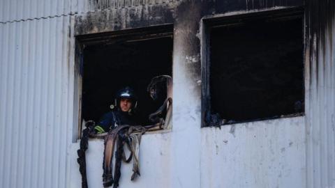 A French Firefighter looks out of a window after extinguishing a fire that broke out overnight at a residential building in a working-class neighbourhood of the southern French city of Nice