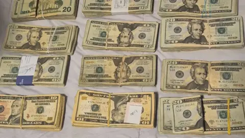 Europol Wads of dollarbills are tied up with rubber bands and laid out in a handout provided by Europol