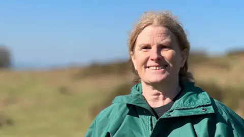 Tracy May on Dartmoor near Lydford and wearing a green coat.
