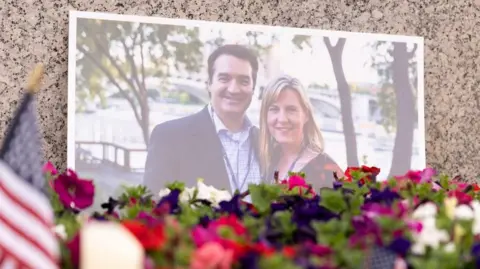 Floral tributes laid in front of a photo of Melissa and Mark Hortman