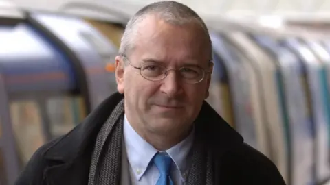 PA Media Peter Hendy stands by a tube train  