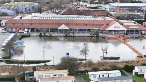 A flooded car park of Tesco in Bognor Regis. The trolley bays are visible but partially filled with water.