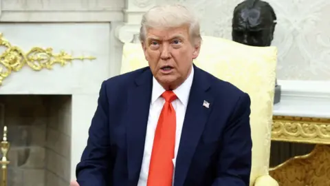 Trump is talking to reporters in the Oval Office.